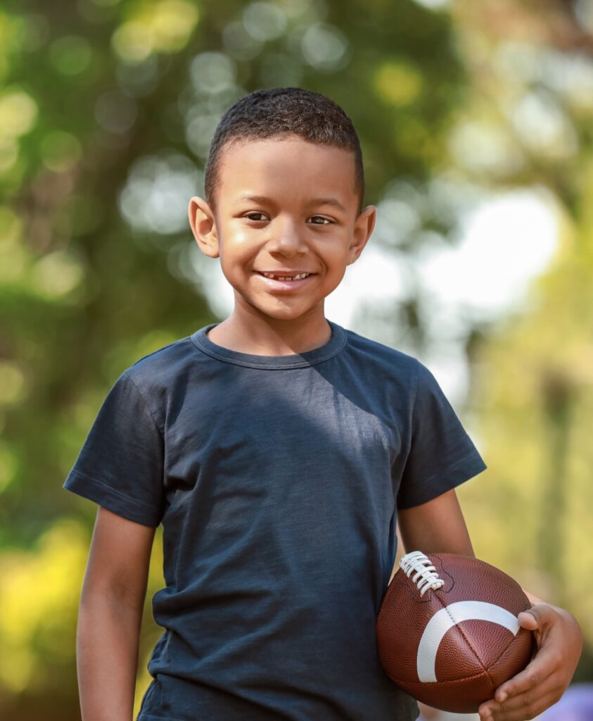 Cute little boy with rugby ball in park