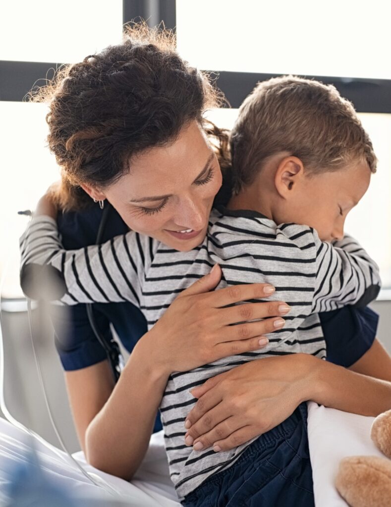 Nurse hugging sick little boy patient in hospital.