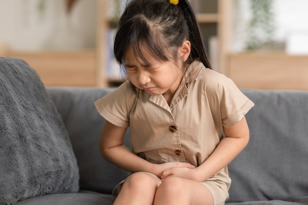 little girl have a stomach ache on couch at home